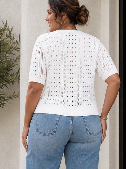Woman wearing a white lace top and blue jeans standing in front of a black door.